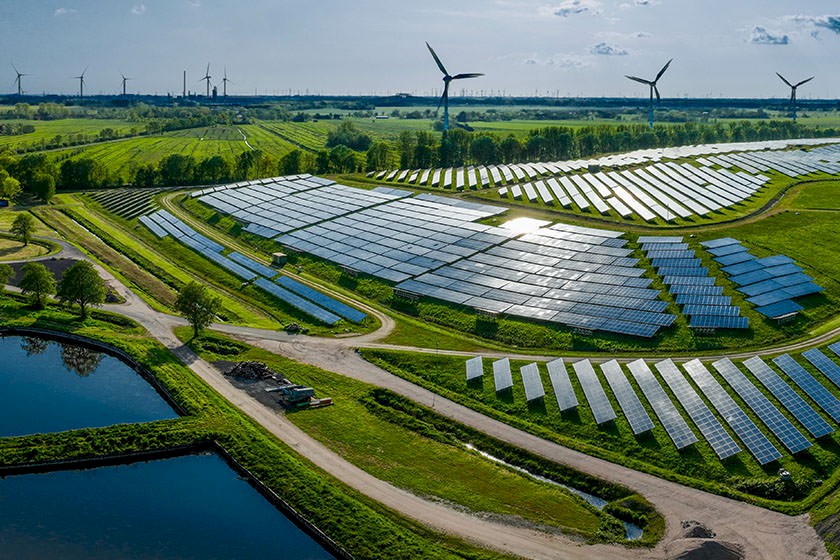 Viele Solaranlagen und ein Windpark in einer grünen Landschaft