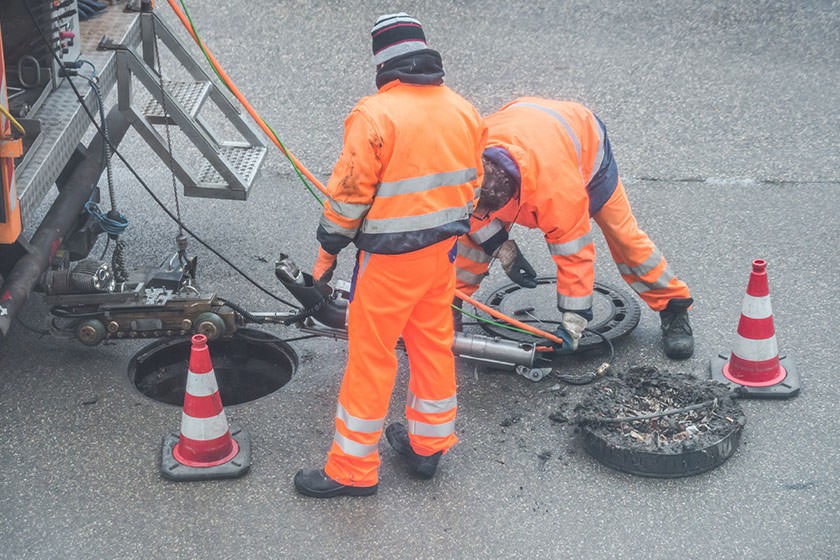 Zwei Personen führen eine Kanalsanierung durch